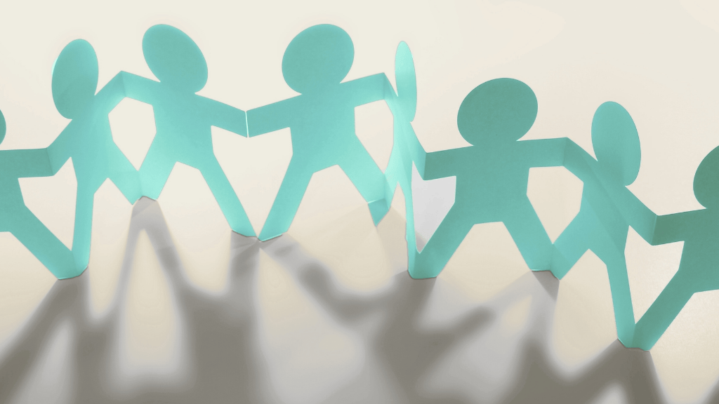 Paper cut-out figures holding hands in a row, symbolising teamwork and collaboration.